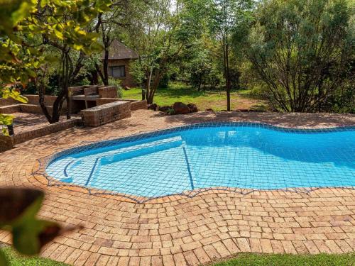 a swimming pool in a yard with a brick patio at Nyala Lodge in Rayton