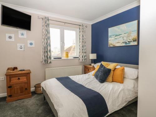 a bedroom with a bed with blue walls and a window at The Willows in Dymchurch