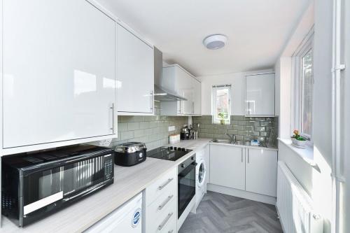 a kitchen with white cabinets and a black microwave at Newark Central Cottage in Newark-on-Trent