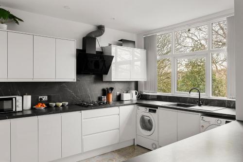 a kitchen with white cabinets and a washing machine at Stylish & Spacious Home in the Heart of Leeds in Central Station