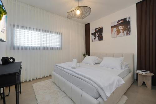 a bedroom with a white bed and a desk at taira suite in Rosh Pinna