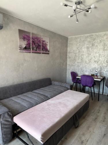 a bedroom with a bed and a table and purple chairs at Aneva home in Ruse