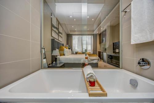a large bath tub in a room with a bedroom at Sandton Skye Unit 1110 in Johannesburg