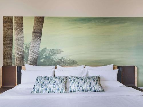 a bed with white pillows and a painting on the wall at Novotel Sao Jose dos Campos in São José dos Campos
