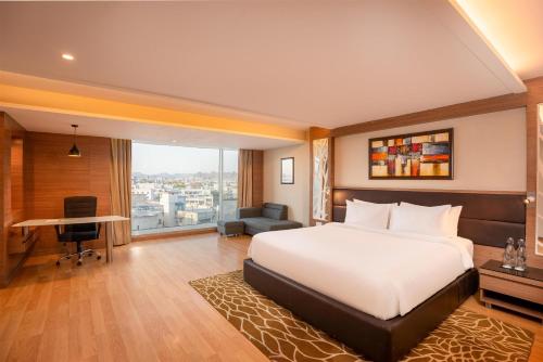 ein Hotelzimmer mit Bett, Schreibtisch und Fenster in der Unterkunft Radisson Udaipur in Udaipur
