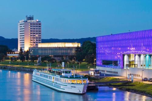 a large white boat docked in front of a large body of water at ARCOTEL Nike in Linz