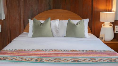 a bed with white pillows and a wooden headboard at Villa Uma Sawan By 25Hours Hospitality in Bedahulu