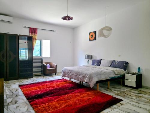 a bedroom with a bed and a red rug at Villa Ross in Saly Portudal