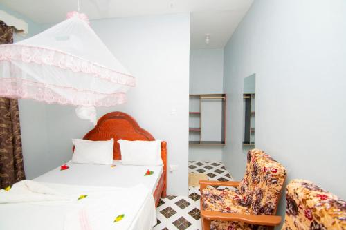 a bedroom with a bed and a chair at Kigwedeni Apartments in Kinyasini