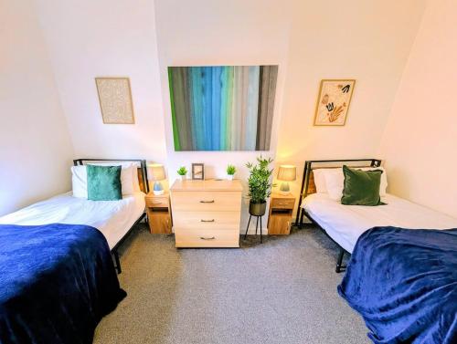 a bedroom with two beds and a dresser and a window at Stylish Townhouse - 8 Mins From Leeds - Free Fast WiFi - Free Parking in Headingley