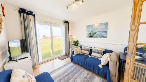 a living room with a blue couch and a tv at F59 Trevone, Riviere Towans in Hayle