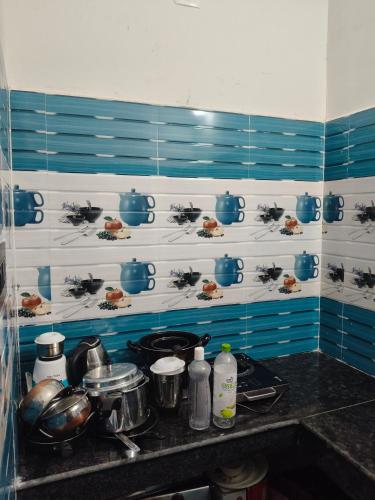 a kitchen with blue and white walls and a stove with pots and pans at 101 Mahalaxmi Homes in Bhubaneshwar