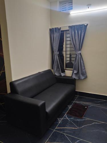 a black couch in a room with a window at 101 Mahalaxmi Homes in Bhubaneshwar