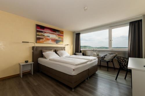 a hotel room with a bed and a large window at City Hotel Heilbronn in Heilbronn