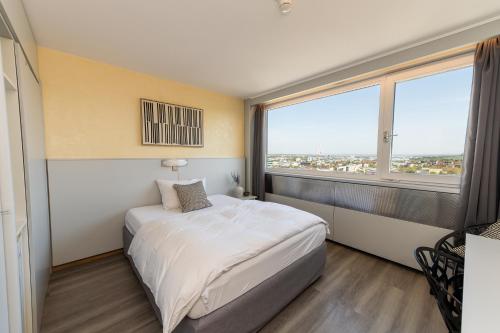 a bedroom with a white bed and a large window at City Hotel Heilbronn in Heilbronn