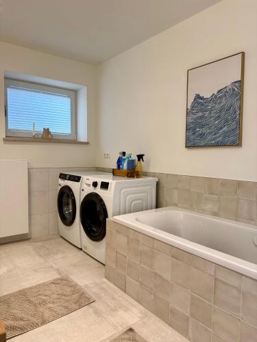 a bathroom with a washing machine and a white tub at Ferienwohnung LANDZEIT in Bad Soden-Salmünster