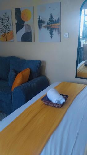 a bedroom with a bed with a blue couch at H&Dluxe in Murangʼa