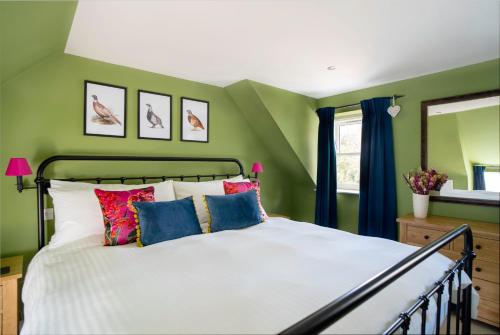 a bedroom with green walls and a bed with colorful pillows at Riverside Cottage in Cairngorms in Ballater