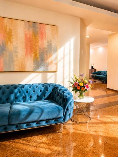 a blue couch in a living room with a vase of flowers at Hotel Athos R.M.T. in Cluj-Napoca
