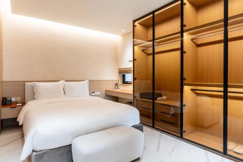 a bedroom with a large white bed and a stool at The Five Hotel & Resort Evara - 24 Hours stay in Dong Anh