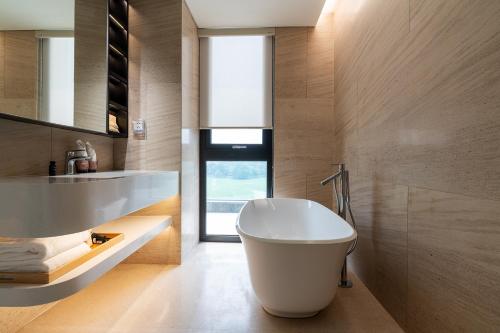a bathroom with a white tub and a sink at The Five Hotel & Resort Evara - 24 Hours stay in Dong Anh