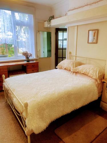 a bedroom with a large white bed with a window at Enstone Homestay in Sidmouth