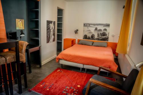 a bedroom with an orange bed and a desk at Le Passage - Gîte 2 à 15 personnes Chartreuse terrasse, calme & nature in Saint-Pierre-dʼEntremont