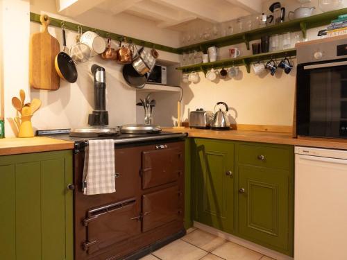 a kitchen with green cabinets and a stove top oven at The Old Cookery Cottage & Free Parking in Goldsborough