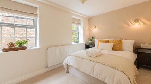a bedroom with a bed and two windows at Newly Renovated 2-Bed Flat | Ripon Town Centre in Ripon