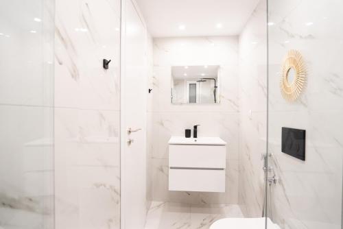 a white bathroom with a shower and a sink at Syntagma Luxury Suites 1 in Athens