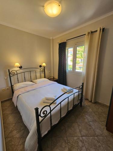 a bedroom with a bed with white sheets and a window at Amfitrion Apartments in Gythio