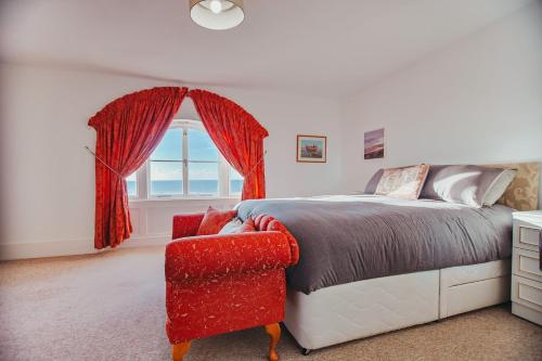 a bedroom with a bed and a chair and a window at The Pelham Penthouse in Hastings