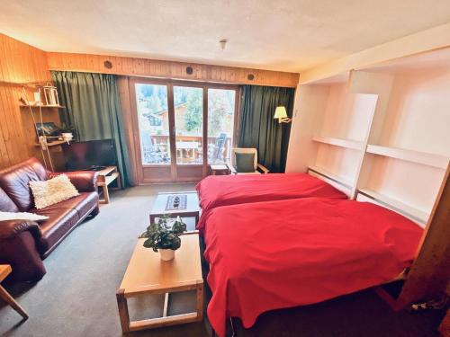 a bedroom with a red bed and a couch at 4 person apartment in central location in Morgins