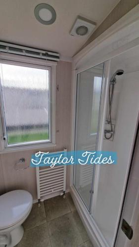 a bathroom with a toilet and a window at Taylor Tides Caravan in Abergele