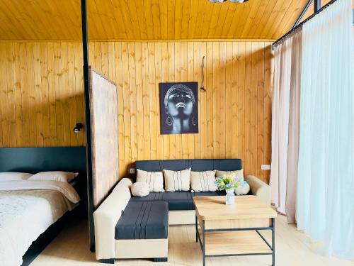 a bedroom with a couch and a bed and a table at Tianuli cottage in Kakhoianebi