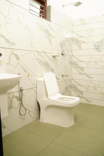 a bathroom with a white toilet and a sink at Twilight Stays Cherai Beach in Pallipuram