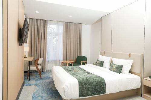 a hotel room with a large bed and a table at NOOMA Hotel Frunze in Bishkek