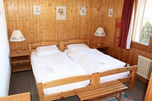 Zwei Betten in einem Holzzimmer mit zwei Lampen in der Unterkunft Pre Vert 44 in Morgins