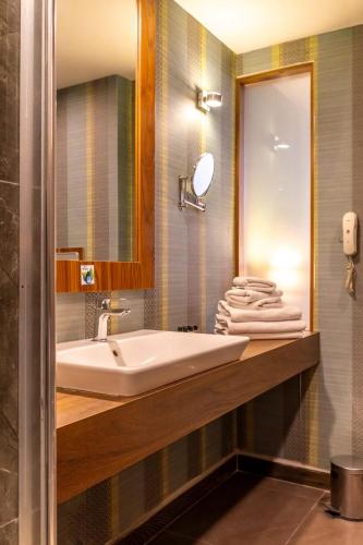 a bathroom with a sink and a mirror and towels at Adana Plaza Hotel in Adana