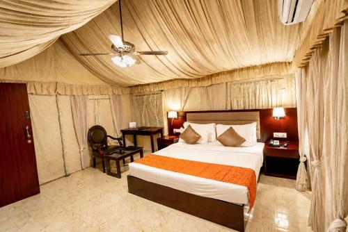 a bedroom with a large bed and a desk and a room at Pride Hotel & Convention Centre Indore in Indore