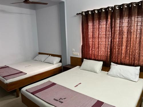 a room with two beds and a window at Velan view in Palni