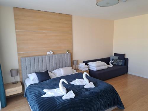 two swans sitting on a bed in a bedroom at Aqua Apartman Panoráma in Velence