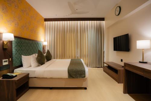 a hotel room with a bed and a television at Akaya Elegance in Ahmadnagar