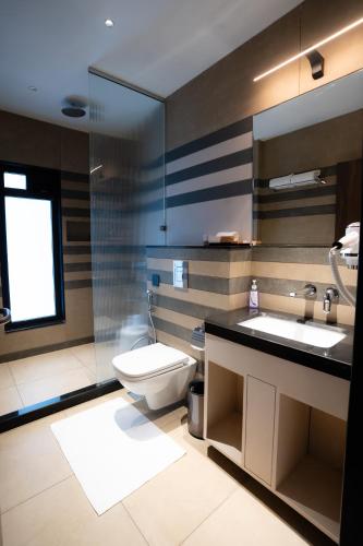 a bathroom with a toilet and two sinks and a mirror at Akaya Elegance in Ahmadnagar