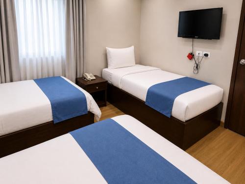 a hotel room with two beds and a flat screen tv at Elysees Hotel I Tahrir Square in Cairo