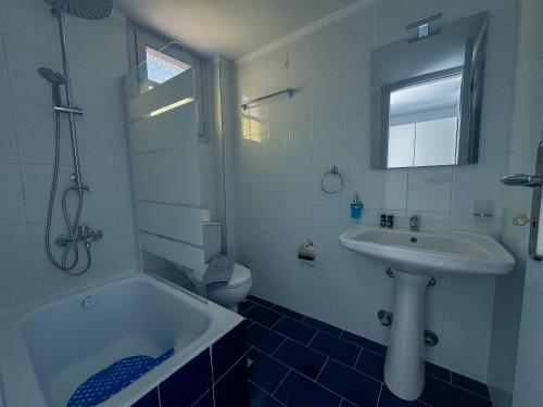 a bathroom with a sink and a tub and a toilet at Tritonas Rooms in Kamari