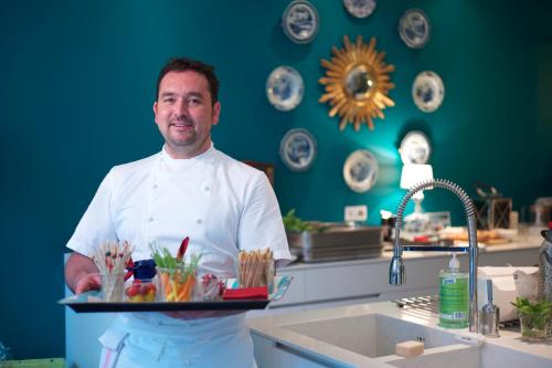 un homme dans une cuisine tenant un plateau de nourriture dans l'établissement Villa du Square, Luxury Guest House, à Paris
