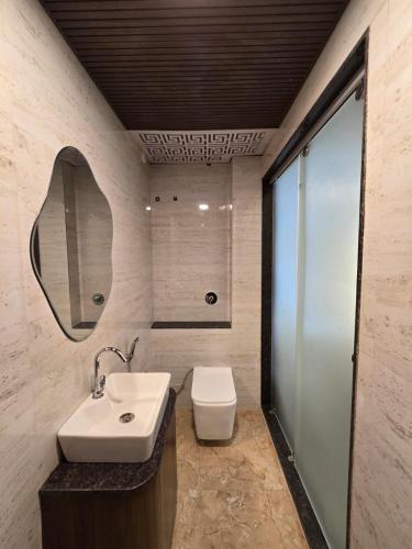 a bathroom with a sink and a toilet and a mirror at Mahak'sVilla in Indore