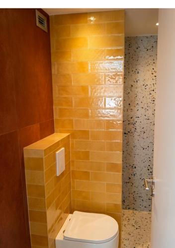 a bathroom with a toilet and a yellow wall at Orchard in Athens