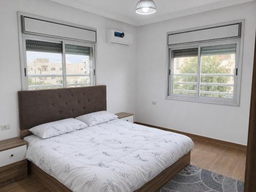 a bedroom with a large bed with two windows at Spacious Apartment in Amman